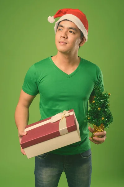 Jovem filipino bonito homem pronto para o Natal contra fundo verde — Fotografia de Stock