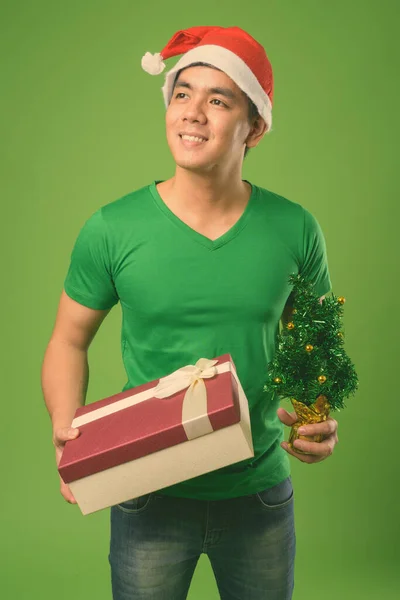 Jovem filipino bonito homem pronto para o Natal contra fundo verde — Fotografia de Stock