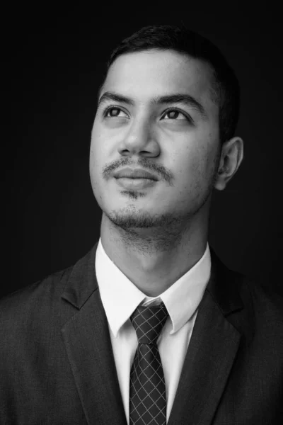 Jonge multi-etnische Aziatische zakenman in pak tegen grijze achtergrond — Stockfoto