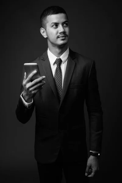 Молодой многонациональный азиатский бизнесмен в иске на сером фоне — стоковое фото