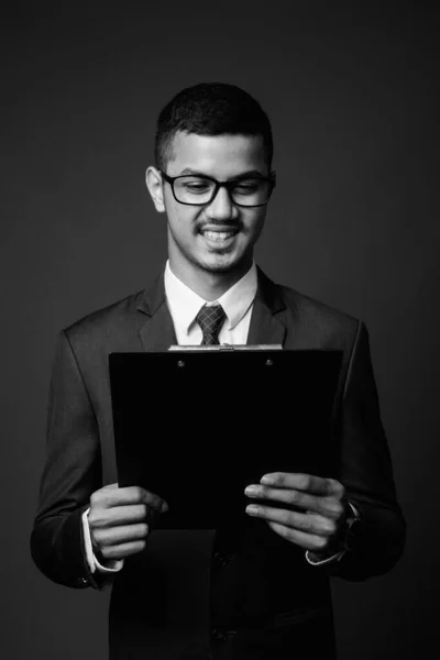 Joven multi étnico asiático hombre de negocios en traje contra fondo gris — Foto de Stock