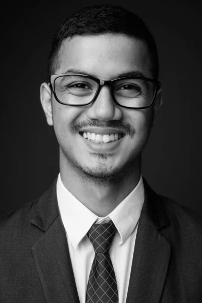 Joven multi étnico asiático hombre de negocios en traje contra fondo gris — Foto de Stock