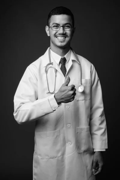 若い多民族アジア人男性医師に対する灰色の背景 — ストック写真