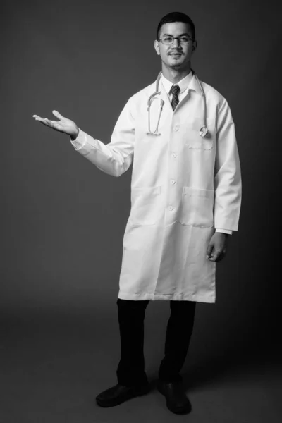 Νεαρός πολυεθνικός Ασιάτης γιατρός άνδρας σε γκρι φόντο — Φωτογραφία Αρχείου