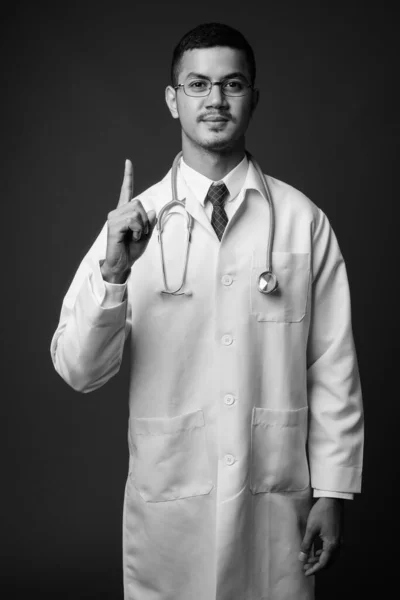 회색 배경에 반대하는 아시아의 젊은 남성 의사 — 스톡 사진