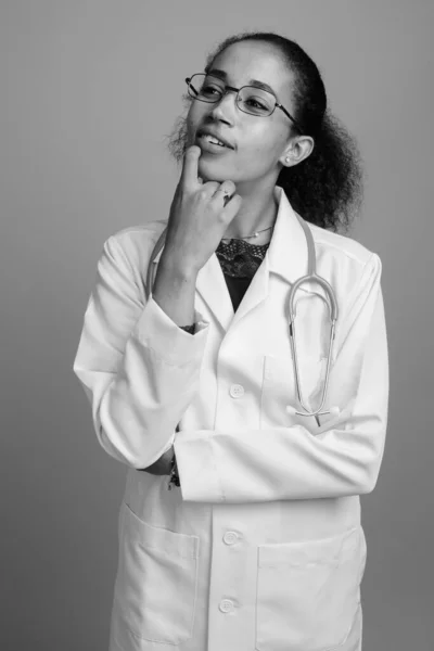Mladá krásná africká žena lékař proti šedé pozadí — Stock fotografie