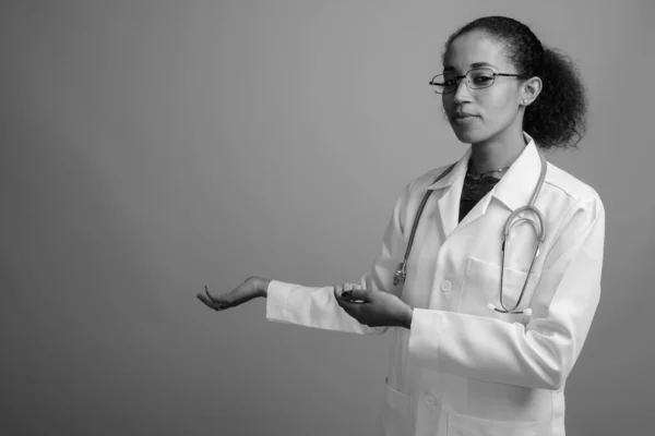 Νεαρή όμορφη Αφρικανή γιατρός γυναίκα σε γκρι φόντο — Φωτογραφία Αρχείου