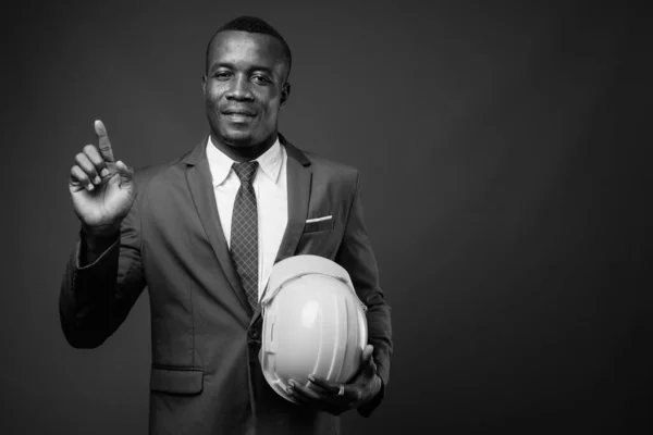 Jeune homme d'affaires africain avec hardhat sur fond gris — Photo