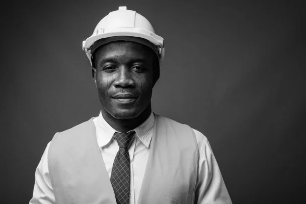 Joven trabajador africano de la construcción contra el fondo gris —  Fotos de Stock
