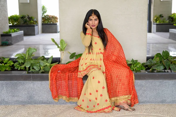 Νεαρή γυναίκα φοράει παραδοσιακό ινδικό φόρεμα ενώ κάθεται — Φωτογραφία Αρχείου