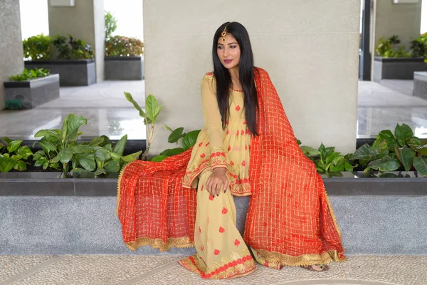 Mujer joven con vestido tradicional indio mientras está sentada —  Fotos de Stock