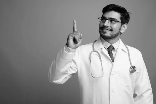 Jovem bonito barbudo persa homem médico contra fundo cinza — Fotografia de Stock