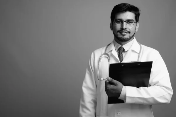 Jovem bonito barbudo persa homem médico contra fundo cinza — Fotografia de Stock