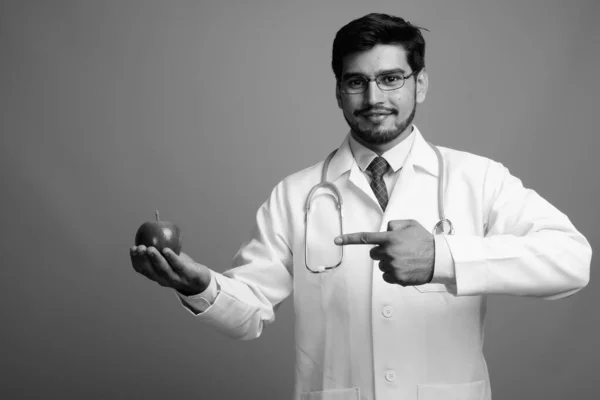 Young handsome bearded Persian man doctor against gray background — Stock Photo, Image