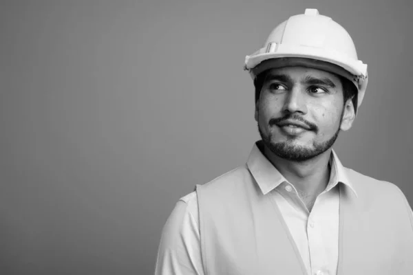 Joven guapo barbudo hombre persa trabajador de la construcción sobre fondo gris — Foto de Stock