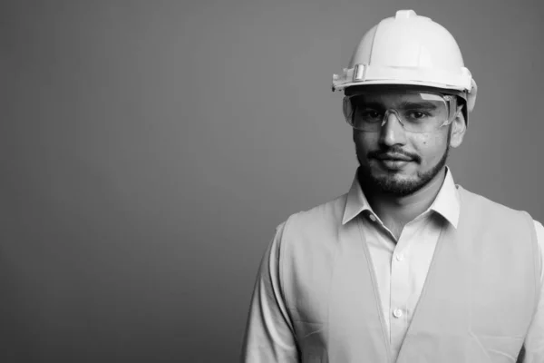 Young handsome bearded Persian man construction worker against gray background — Stock Photo, Image