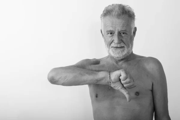 Estúdio tiro de belo homem barbudo sênior dando polegar para baixo sem camisa contra fundo branco — Fotografia de Stock