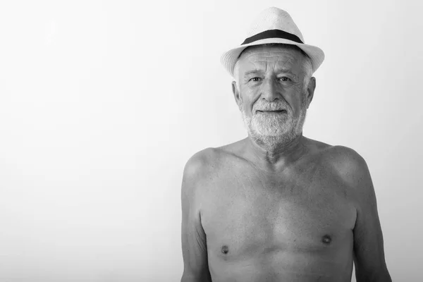 Studio shot of handsome senior bearded man wearing hat shirtless against white background — Stock Photo, Image