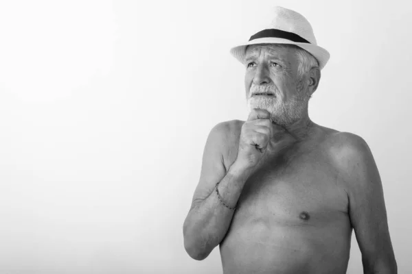 Studio colpo di bello anziano barbuto uomo pensando mentre guardando verso l'alto e indossando cappello senza maglietta contro sfondo bianco — Foto Stock