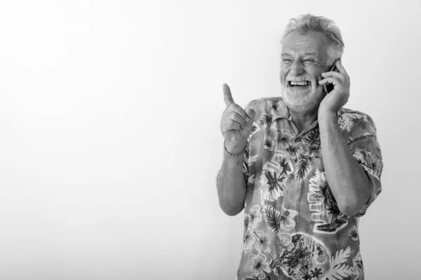 Düşünceli, mutlu, yaşlı, sakallı, gülümseyen ve cep telefonuyla gülen bir turistin stüdyo fotoğrafı. — Stok fotoğraf