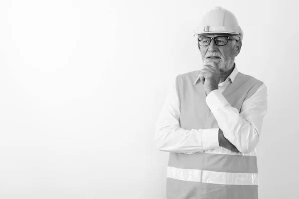 Studio colpo di bel anziano barbuto lavoratore edile pensare con mano sul mento e indossare occhiali su sfondo bianco — Foto Stock