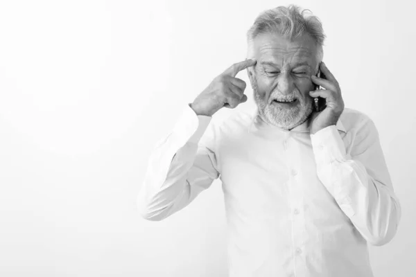 Στούντιο πλάνο του θυμωμένος ανώτερος γενειοφόρος άνθρωπος σκέψης, ενώ μιλάμε στο κινητό τηλέφωνο σε λευκό φόντο — Φωτογραφία Αρχείου