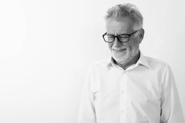 Studio colpo di triste anziano barbuto uomo pensando mentre guardando verso il basso con gli occhiali contro sfondo bianco — Foto Stock