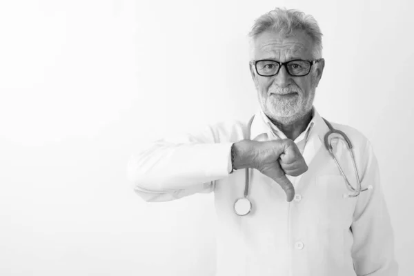 Studio colpo di bello anziano barbuto uomo medico dando pollice verso il basso contro sfondo bianco — Foto Stock