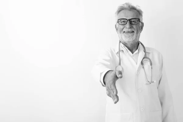 Studio colpo di felice anziano barbuto uomo medico sorridente mentre dà stretta di mano contro sfondo bianco — Foto Stock