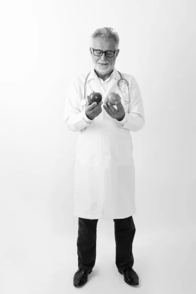 Pieno colpo del corpo di bello anziano barbuto uomo medico in piedi mentre tiene due mele — Foto Stock
