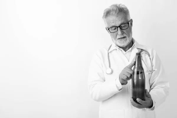 Studio colpo di bello anziano barbuto uomo medico in possesso e la misurazione bottiglia di birra su sfondo bianco — Foto Stock