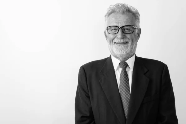 Primo piano di felice anziano uomo d'affari barbuto sorridente mentre indossa occhiali su sfondo bianco — Foto Stock