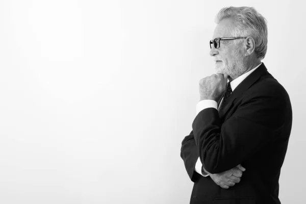Profilo vista di bello anziano barbuto uomo d'affari pensando mentre indossa occhiali contro sfondo bianco — Foto Stock
