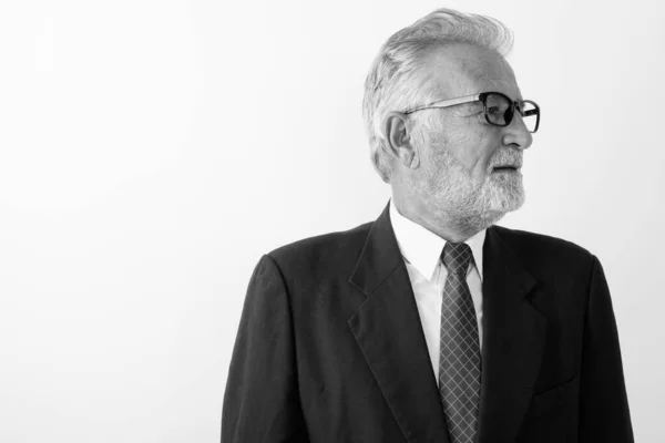 Profilo vista di bello anziano barbuto uomo d'affari pensando e guardando la distanza mentre indossa occhiali su sfondo bianco — Foto Stock