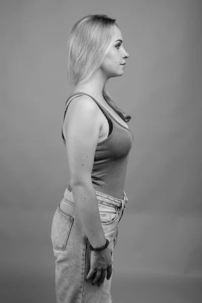 Giovane bella donna con i capelli biondi contro sfondo grigio — Foto Stock