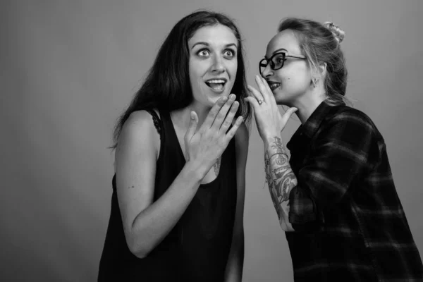두 젊고 아름다운 여자가 회색 배경을 반대하는 친구들 — 스톡 사진