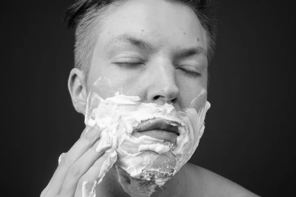 Jonge knappe man shirtless terwijl grooming tegen grijze achtergrond — Stockfoto