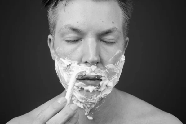Jonge knappe man shirtless terwijl grooming tegen grijze achtergrond — Stockfoto