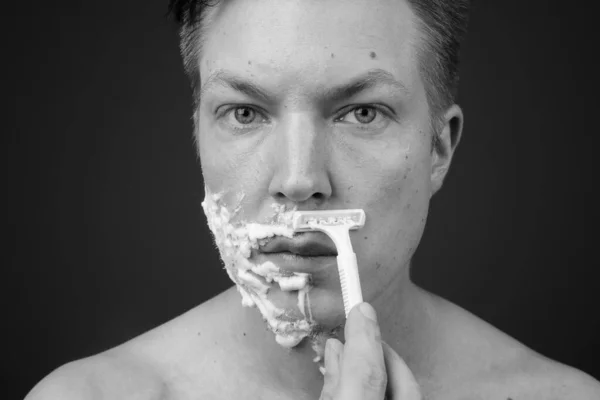Jovem bonito homem sem camisa enquanto grooming contra cinza fundo — Fotografia de Stock