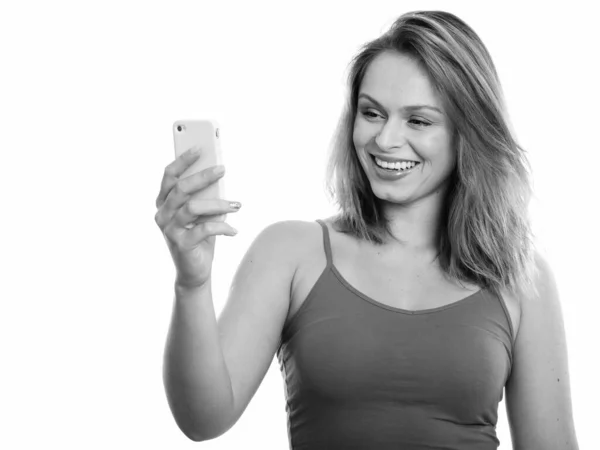 Studioaufnahme einer jungen glücklichen Brasilianerin, die mit dem Handy lächelt — Stockfoto
