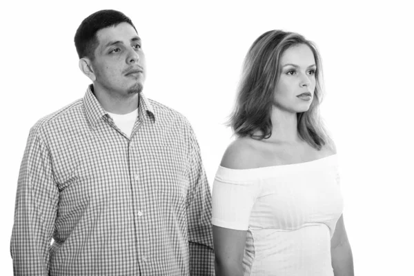 Studio shot of young couple thinking while looking away together Stock Picture