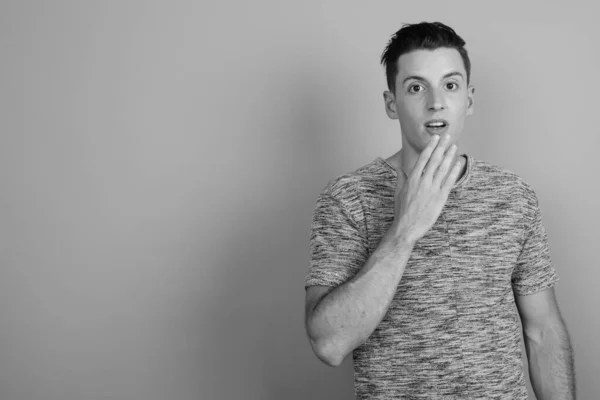 Young handsome man wearing gray shirt against gray background — Stock Photo, Image