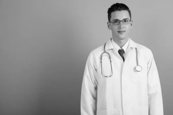 Joven hombre guapo médico contra fondo gris — Foto de Stock