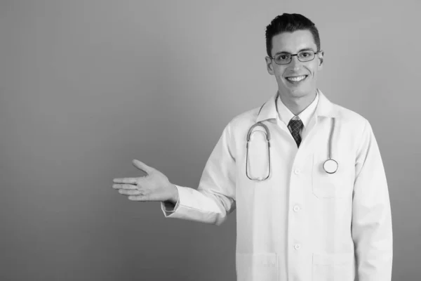 Young handsome man doctor against gray background — Stock Photo, Image