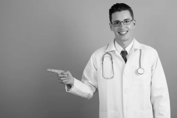 Fiatal jóképű férfi orvos ellen szürke háttér — Stock Fotó