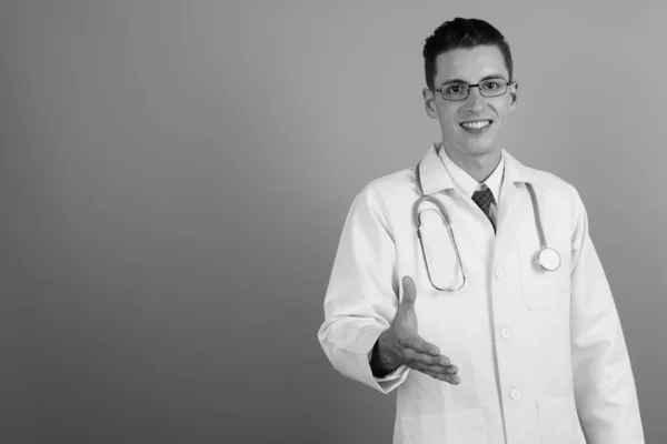 Young handsome man doctor against gray background — Stock Photo, Image