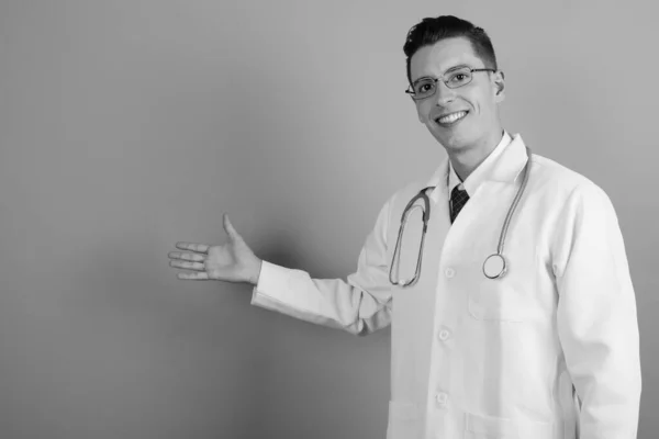 Young handsome man doctor against gray background — Stock Photo, Image