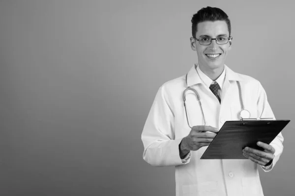 Joven hombre guapo médico contra fondo gris — Foto de Stock