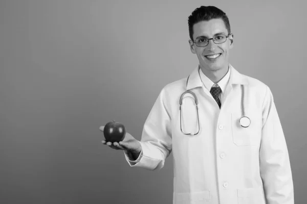 Νεαρός όμορφος άντρας γιατρός σε γκρι φόντο — Φωτογραφία Αρχείου