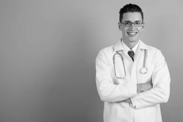 Joven hombre guapo médico contra fondo gris — Foto de Stock
